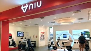 Image of a Niu (NIU) storefront with scooter showroom inside and shoppers